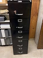 Photo of black 5-drawer filing cabinet made by Century Art Steel Co. showing front with handles and label holders on drawers.