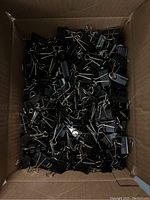 Box containing a large quantity of new black binder clips with silver metal handles.