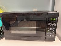 Front view of the black Insignia microwave showing digital display and control panel.