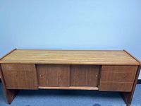 Front view of wood finish credenza showing drawers and central sliding door section.