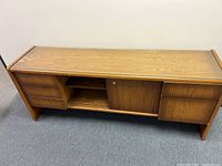 Front angle view of the wooden credenza showing four drawers on the left side, and a middle open shelf covered by sliding door, plus the right side drawers.