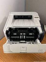 Front view of HP LaserJet P2055dn printer with front paper tray open showing internal mechanism