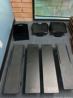 Black perforated metal monitor risers, two solid black plastic organizers with compartments