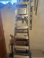 Front view of 6 ft aluminum ladder folded against basement wall