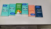 Six individual Kleenex tissue packs with motivational print designs in various colors and styles lined up horizontally.