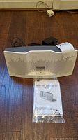 Bose SoundDock XT speaker with front perforated grill and docking slot. Power adapter cable visible.