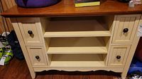 Front view of wooden buffet table showing stained top, cream painted base with four drawers and two central shelves