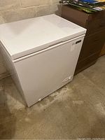 White Magic Chef chest freezer with top-opening lid seen in basement environment.