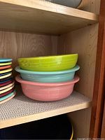 Three ceramic bowls in pastel colors stacked on top of each other: lime green, light blue, and coral pink.