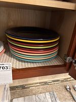 Stack of colorful large dinner plates in a cabinet.