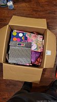 Open box showing assorted folded holiday gift bags stacked inside, including polka dot and floral patterned bags.