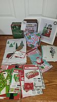 Photo showing multiple holiday-themed treat boxes, bags, blank cards, and a framed holiday photo arranged on the floor.