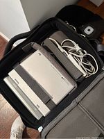 Portable DVD player secured with straps inside a black carrying case, includes charging cable
