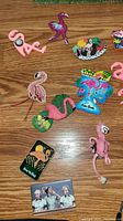Top view of various flamingo and novelty magnets on wood surface, showing different materials and designs.