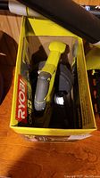 Yellow and black Ryobi handheld blower tool in box with nozzle visible