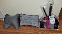 Photo of two throw pillows and a flamingo-themed dustpan and broom set on wooden floor.