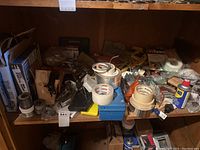 Full view of shelf with assorted hand tools, tapes, spray cans, and small hardware items scattered