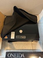 BakerStone oven partially covered with black carrying case, original Oneida box nearby.