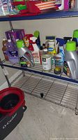 Wide view of shelf with various cleaning product bottles and sprays including pet cleaner, all-purpose cleaner, and Swiffer bottles.