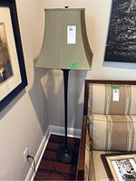 Full view of the floor lamp placed between a framed picture and a couch in a corner of a room, with the green shade clearly visible.