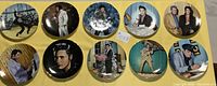 Full view of all 10 Elvis Presley plates on yellow cloth background showing various images of Elvis in performance and casual settings.