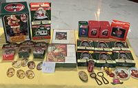 Overview of all Coca Cola lot items including mechanical Santa bank, Trim Tree house ornaments, vintage pins, bottle openers, holiday cards, and small collectibles.