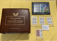 Wide shot of the brown Golden Replicas binder alongside a framed Bugs Bunny collectible and several individual stamps displayed in plastic holders on a yellow background.