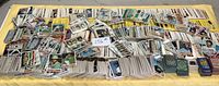 Wide view of extensive baseball card collection spread over a table, showing loose cards and stacks of assorted cards.