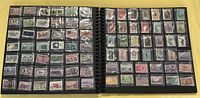 Open scrapbook pages showing multiple rows of postage stamps in various colors and designs, each held in clear plastic pockets on black pages.