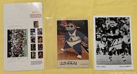 Sports paper items displayed flat on a yellow surface, showing a printed sheet with NFL player images, the Big Shot basketball mascot postcard, and a black and white photo postcard of Troy Aikman in Dallas Cowboys uniform.