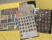 Top view of multiple sheets with postage stamps in protective sleeves and small plastic bags.