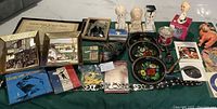 Vintage lot displayed on a green cloth including framed photographs, ceramic figurines, colorful painted decorative item, hip pocket records in sleeves, and various vintage memorabilia.