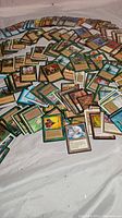 Photo showing a wide array of Magic: The Gathering cards scattered on a surface, with various colors and border styles visible.