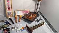 Photo of beer tap handles, wooden signs, wall light, playing cards and bar game items arranged on white cloth.