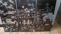 Full view of three black lacquer panels side by side showing continuous mother-of-pearl inlaid scenes of traditional Chinese countryside life with people, animals, and plants.