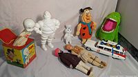 Full lot of collectibles including Casper music box, Michelin Man doll, Pillsbury Dough Boy, Flintstones Fred plush, Ghostbusters items, and handmade dolls.