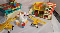 Photo showing entire Fisher Price airport playset, parking garage, two yellow planes, white/orange plane, and service vehicle.