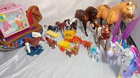 Wide shot of all horse figurines, lunchbox and toys arranged together on a white surface
