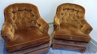 Pair of golden brown crushed velvet mid century swivel rocking chairs with tufted backs and plush seats shown from front angle