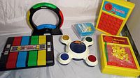 Photo showing all five games including Simon, Super Simon, Max Back Talk electronic games and two Perfection games with pieces.