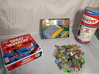 Lot showing Space Invaders board game box, Cyberminds puzzle in box and loose puzzle pieces, and vintage Wiker Toy cylindrical container