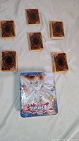 Stacks of Yu-Gi-Oh! trading cards from the back, arranged around a Yu-Gi-Oh! tin featuring Blue-Eyes White Dragon artwork.