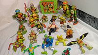 Full view of all TMNT action figures arranged with lunch box in background showing the lot contents and variety of characters.