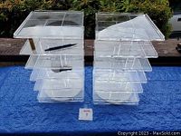 Two clear plexiglass rotating display units side by side on a blue surface outdoors, showing overall size and construction.