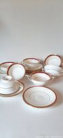 Eight sets of white porcelain two-handled cream soup bowls with matching underplates arranged on a white background, showing front and sides.