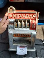 Front view of the cast mini Reno Nevada slot machine held by a hand showing detailed embossed lettering and reels.