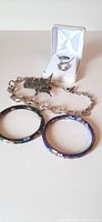 Photo shows entire lot including two cloisonné bangles, silver toggle necklace with angel bookmark charm, and Swarovski crystal necklace in box.