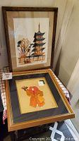 Photo showing both framed art pieces: watercolour of Toji Temple Pagoda and framed fabric art of Japanese figure