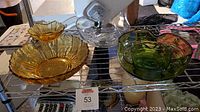 Top view of MCM style chip and dip bowls in amber, green, and clear glass on metal shelves, showing the set and colors.