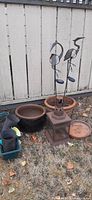 Outdoor lot including Moroccan style metal lantern, two metal bird sculptures, multiple planters and pots in various materials and colors